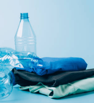 Recycled plastic bottles next to folded sustainable fabrics, highlighting eco-friendly textile production.