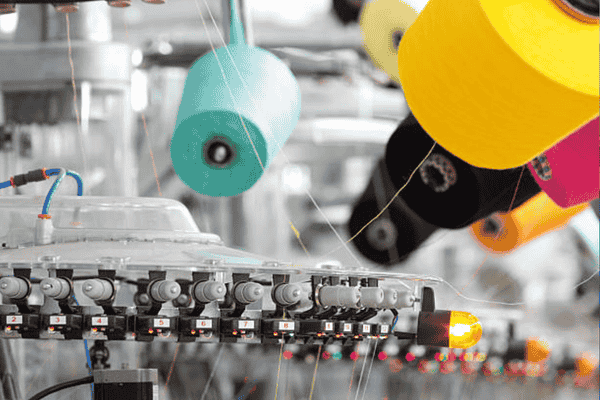 Sewing machine with colorful thread spools in a workshop.