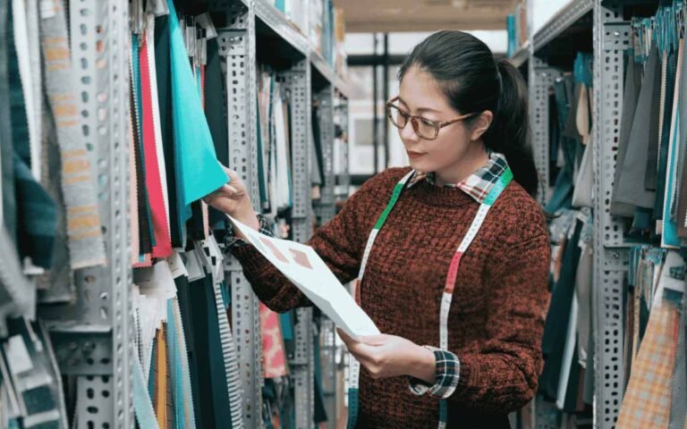 Woman examining fabric samples in a textile warehouse.